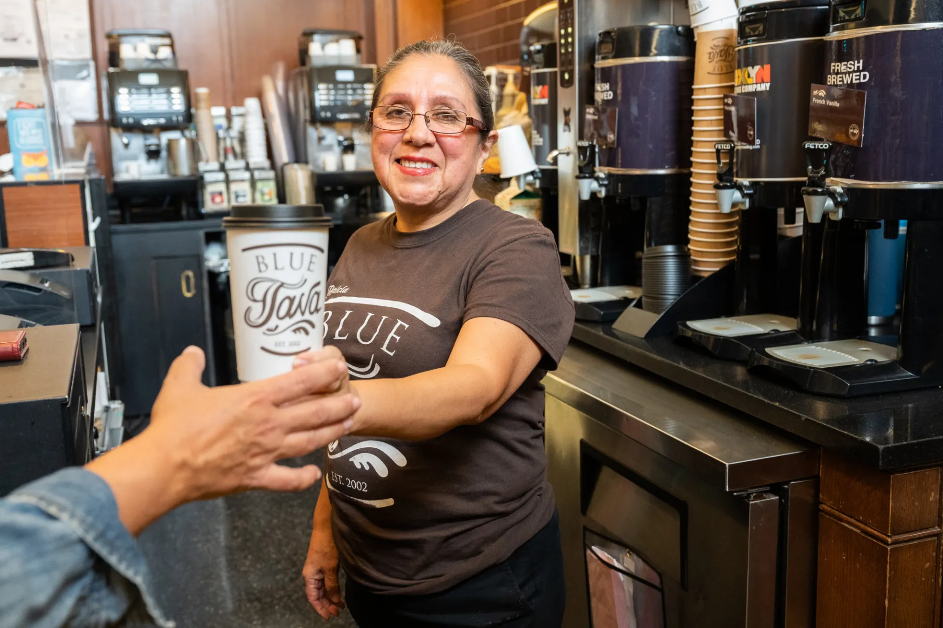 Blue Java Butler employee handing coffee to customer