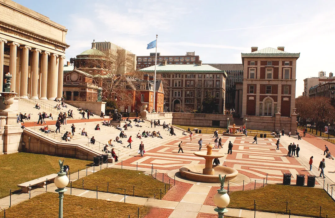 Columbia Campus photo in front of low library. Students sitting on the steps, and walking around a nice, bright day.